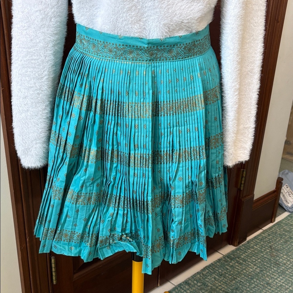 Aqua Apron  Micro pleated 
Gold patterned print 18.5”L
NWOT needs iron
